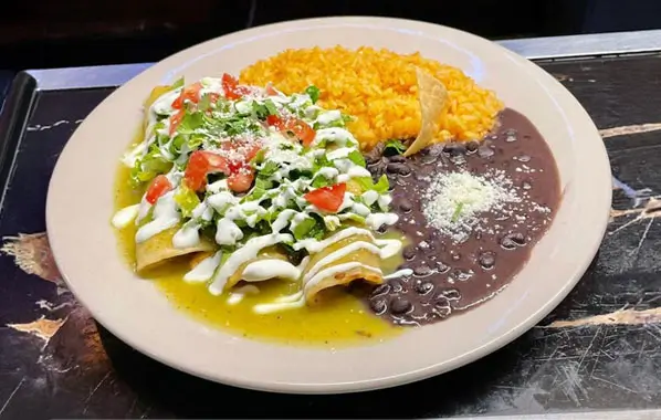 A table filled with traditional Mexican cuisine at El Texano Restaurant & Bar, showcasing tacos, guacamole, rice, beans, and salsa.