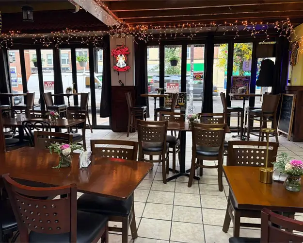 A restaurant interior featuring several tables and chairs arranged in the center of the room.
